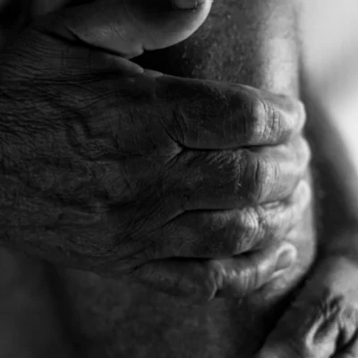 free photo of wrinkled hands of an elderly man gripping his leg below the knee